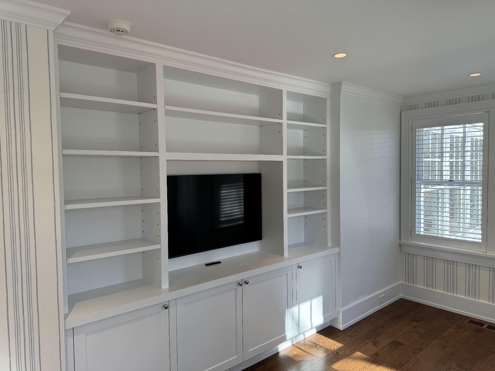 Painted built-in media wall with adjustable shelves and Shaker-style cabinets