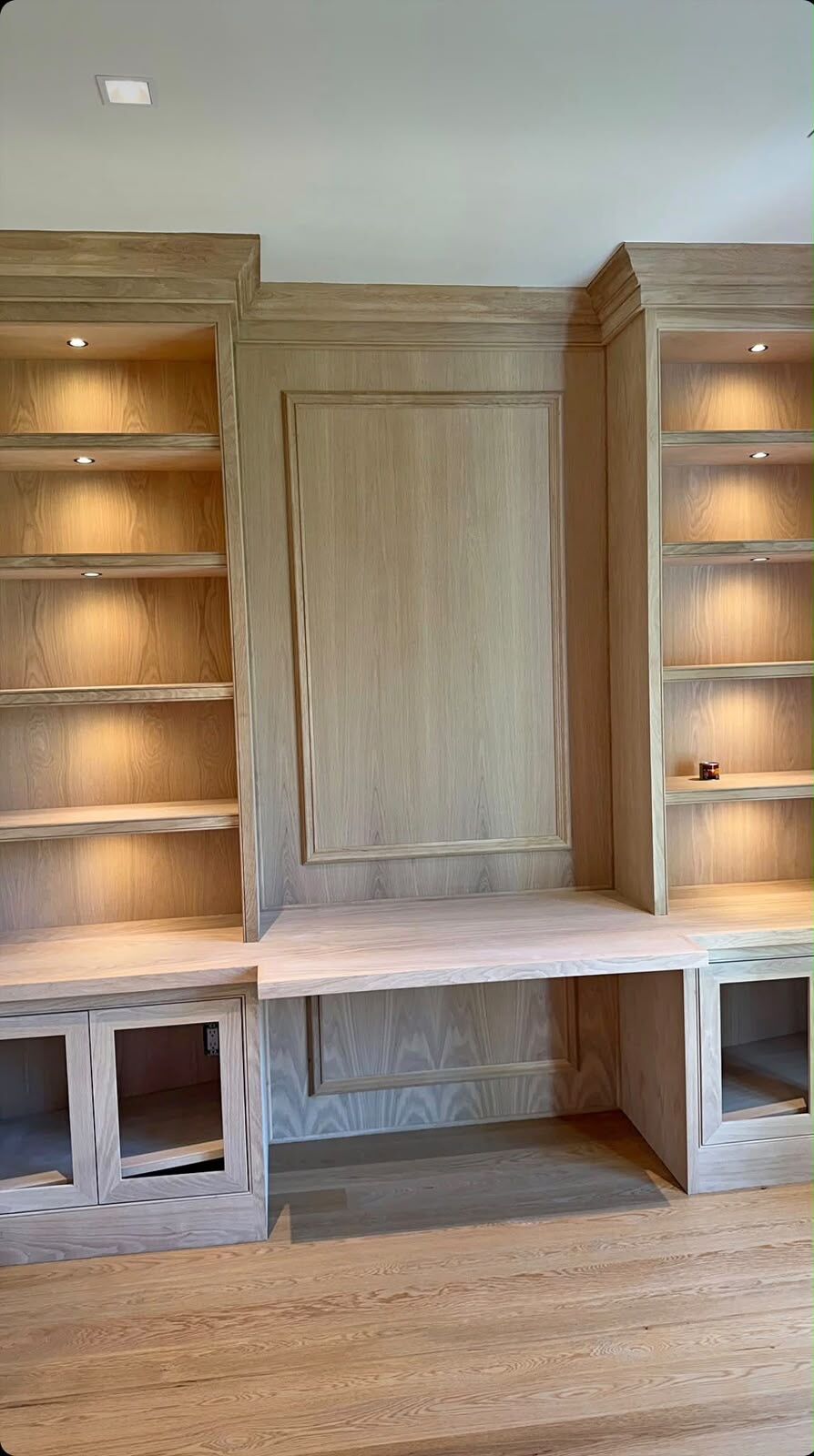 Paneled center section with applied molding between white oak bookcases